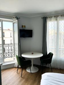 a room with a table and chairs and a bed at Studio de charme parisien in Levallois-Perret