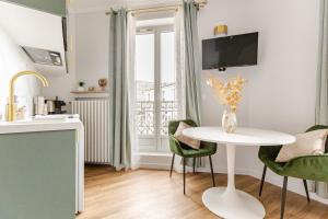 a kitchen with a white table and green chairs at Studio de charme parisien in Levallois-Perret