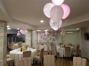 un salón de banquetes con mesas blancas y globos rosas en Hotel Solar, en Focşani