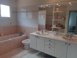 ein Badezimmer mit zwei Waschbecken und einer Badewanne und einer Toilette in der Unterkunft Villa de standing avec gd jardin arboré près d'Argelès sur Mer in Saint-André