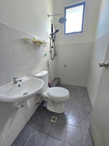 a bathroom with a white toilet and a sink at Zuta Homestay in Papar +10 photos