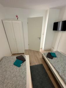 a room with two beds and a door with a television at Modernes Apartment in Ruhiger Lage in nähe des Fischereihafens in Bremerhaven