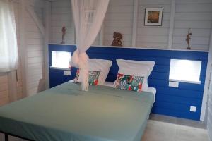 Un dormitorio con una cama azul y blanca con almohadas en Tikazbleue 2024 Maison entière chez l'habitant, en Sainte-Rose 24 fotos más