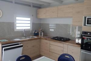 cocina con armarios de madera, fregadero y fogones en Tikazbleue 2024 Maison entière chez l'habitant, en Sainte-Rose