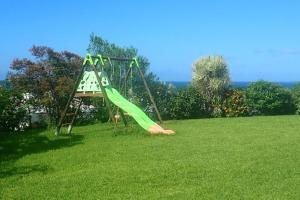 Un tobogán en un patio con césped y una zona de juegos en Tikazbleue 2024 Maison entière chez l'habitant, en Sainte-Rose