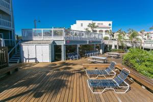 a deck with two chairs and a table and benches at St Augustine Beach Luxury Resort Condo in Saint Augustine