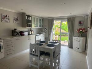 a white kitchen with a table and chairs in it at Lagoon Views at Langebaan in Langebaan