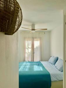 Un dormitorio con una cama azul y un ventilador de techo. en Casita Estrella, en Arenal d'en Castell