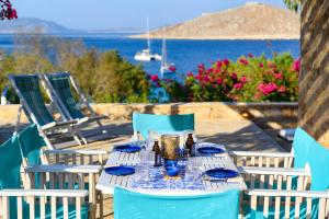 a table with blue and white chairs and a view of the water at Villa Ftenagia in Halki