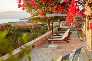 a row of benches with an umbrella and the ocean at Villa Ftenagia in Halki