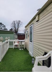 un patio con tavolo e sedie accanto a una casa di Cairnryan Heights home from home a Cairnryan