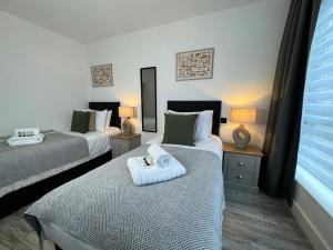 a hotel room with two beds with towels on them at Central City Two-Bedroom in Swindon