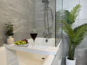 a bath tub with a glass of wine and a bowl of fruit at Central City Two-Bedroom in Swindon