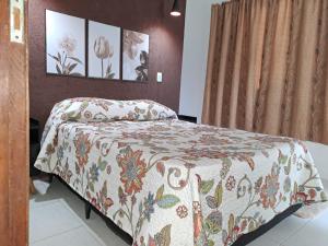 a bedroom with a bed with a flowered blanket on it at Jay's Home Stay in Cotia
