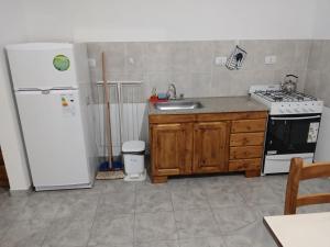 a kitchen with a white refrigerator and a sink at Departamentos Los dos Pinos in San José