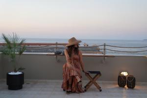 a woman wearing a hat standing next to the ocean at Porta Harenae Residencia in Chania