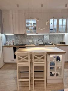 a kitchen with white cabinets and a island with stools at WYSPA MEW - apartament PREMIUM z prywatnym ogrodem, 150 m od plaży in Gąski
