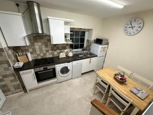 a kitchen with a table and a clock on the wall at Cosy 2 Bedroom Cottage in Betws y Coed, Snowdonia in Betws-y-coed