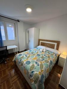ein Schlafzimmer mit einem Bett mit einer bunten Decke darauf in der Unterkunft Apartamento Santander, Playa Sardinero in Santander
