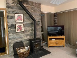 a living room with a wood stove and a television at Tyn Y Fron 6 bedroom house in Betws-y-Coed Snowdonia in Betws-y-coed