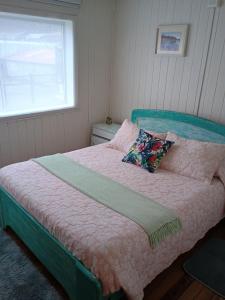 a bedroom with a bed with a pink blanket and a window at Vintage Hostal in Puerto Montt