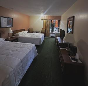 ein Hotelzimmer mit zwei Betten und einem Fernseher in der Unterkunft The Fort Hotel in Fort Nelson