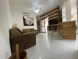 a living room with a couch and a television at Paraíso Condomínio Wembley Tênis G-302 in Ubatuba +149 photos