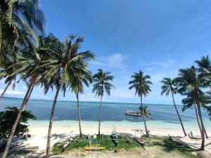 a beach with palm trees and a boat in the water at Absolute Beachfront Studio with Kitchen & Balcony in Boracay