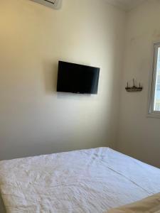 Un dormitorio con una cama y un televisor de pantalla plana en la pared. en Ubatuba - Recanto Praia das Toninhas, en Ubatuba