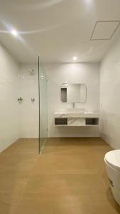 a white bathroom with a toilet and a sink at Nio Garden Hotel in Sumbawa Besar