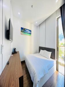une chambre blanche avec un lit et une télévision dans l'établissement VILLA 16 phòng ngủ - SONASEA - VÂN ĐỒN - sát biển - đầy đủ tiện nghi, à Thâm Câu