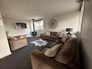 a living room with a brown couch and a table at Lakeside by Ruataniwha in Twizel