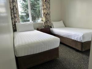 two beds sitting next to a window in a room at Lakeside by Ruataniwha in Twizel
