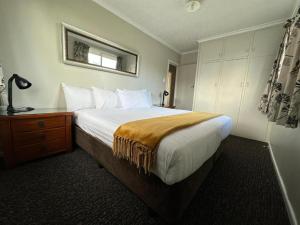 a bedroom with a large bed and a dresser with a mirror at Lakeside by Ruataniwha in Twizel