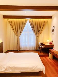a bedroom with a bed and a table and a window at Kashgar QiuGe Homestay in Kashgar +77 photos