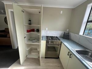 a small kitchen with a stove and a sink at Lakeside by Ruataniwha in Twizel