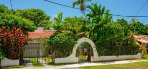 a house with a white gate and trees at Entire private Beautiful 2 Bedroom plus Den House with gated front&back yard and Free parking 10min drive to Miami Beach in Miami
