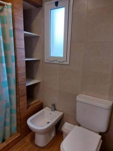 a bathroom with a toilet and a sink and a window at Casa alquiler temporal Santa Clara del Mar in Santa Clara del Mar