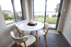 a white table and chairs in a room with windows at Haven House - River Edge Apartment in Rosevears