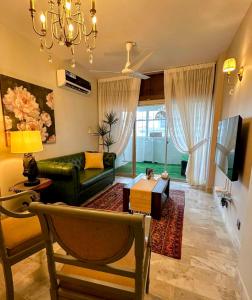 a living room with a green couch and a table at Oceanfront Oasis - Steps to Dolmen Mall in Karachi