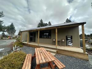 a small building with a picnic table and a bench at Lake Ruataniwha Holiday Park in Twizel