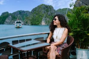 a woman sitting at a table on a boat at Venezia Cruises in Ha Long