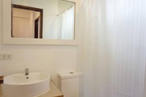 a white bathroom with a sink and a mirror at Two Bedroom Affordable Beach Front House in Boracay +15 photos