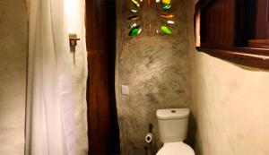 a bathroom with a toilet and a chandelier on the wall at BioChalé Buena Vista in Sao Jorge