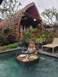 una ragazza seduta in piscina in una piscina circolare di Teba Junjungan Cottages ad Ubud