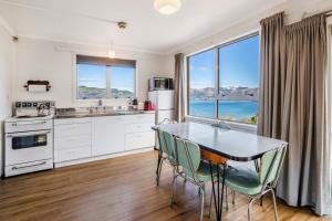 cocina con mesa y sillas y ventana grande en New Farm - Akaroa Holiday Home, en Akaroa