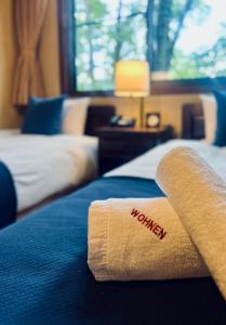 a hotel room with a welcome towel on a bed at Hotel Wohnen in Hakuba