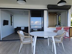 a white table and chairs on a patio with the ocean at Raina Lodge - Fare Oriana - Piscine privée in Haapiti