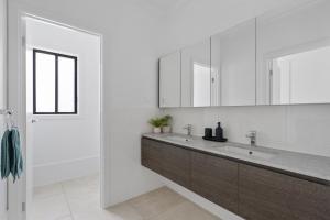 a white bathroom with a sink and a mirror at Caves Beach Getaway in Caves Beach +28 photos