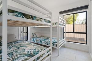 two bunk beds in a room with a window at Caves Beach Getaway in Caves Beach